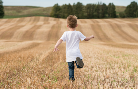 little boy running in a farmfield