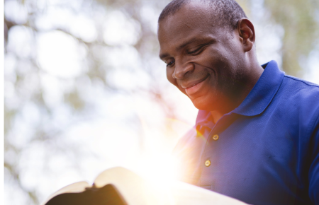  man reading the Bible outside with sun pouring in