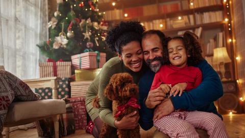 A family embraces in front of a warm Christmas scene 